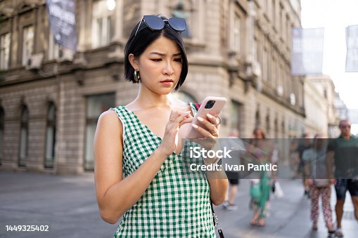 istock Serious Asian woman text messaging on smart phone in the city. 1449325402