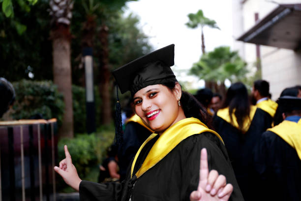 istock Cheerful women portrait wearing cap and gown during convocation day 1449325732