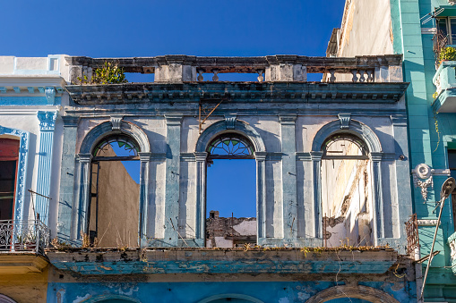 Havana, Cuba - October 23, 2022: Low-angle view of the facade of a dilapidated building with broken windows. There are no people on the scene.