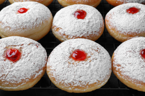istock Many delicious donuts with jelly and powdered sugar on cooling rack, closeup 1449327852