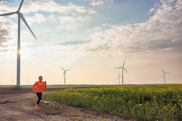 istock Young woman running in windfarm fields, staying in motion 1449328039