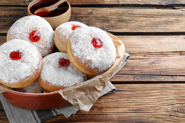 istock Delicious donuts with jelly and powdered sugar in baking dish on wooden table. Space for text 1449328154