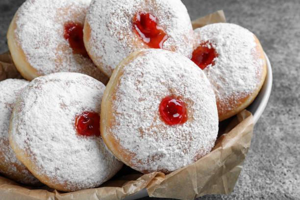 istock Delicious donuts with jelly and powdered sugar in bowl on grey table, closeup 1449328245
