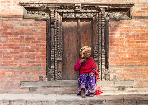 Senior woman sitting on the steps of a historic building in Bhaktapur, Nepal