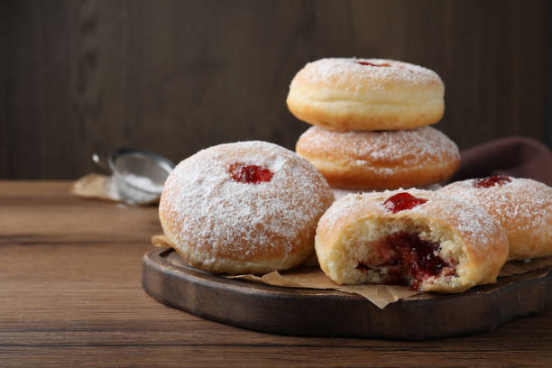 istock Delicious donuts with jelly and powdered sugar on wooden table 1449328984