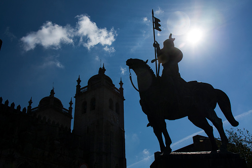 Porto, Portugal- May 4, 2011:Porto Cathedral, Se Catedral do Porto and horseman medieval warrior statue, Vimara Peres, first Count of Portugal in the 9th century. Portugal. Back lit,outlined, sun beam.