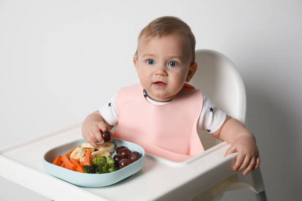 istock Cute little baby wearing bib while eating on white background 1449333453