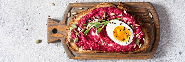 istock Whole grain toast with beetroot hummus, seeds, egg and microgreens (sprouted pea sprouts) on a light gray background. The concept of healthy eating. 1449334651