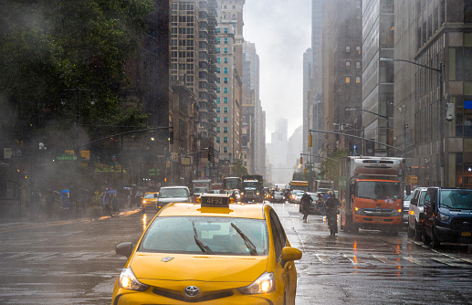 Daily life during a rainy day on the 40th street in Manhattan. Taxi and steam coming out from from the manholes in the background. New York City, Usa. Manhattan is the most densely populated borough of New York City.