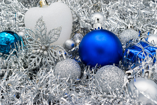 Christmas decoration in white, silver and blue, with garlands, Christmas balls, flowers and a white heart.