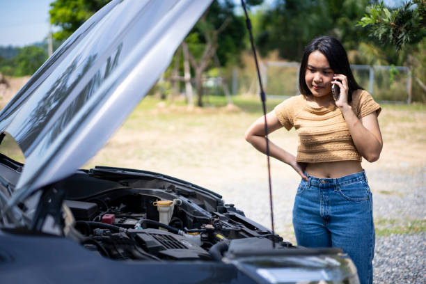 istock Young Asian woman using a mobile phone to call the mechanic while looking at broken down car on street. 1449339609