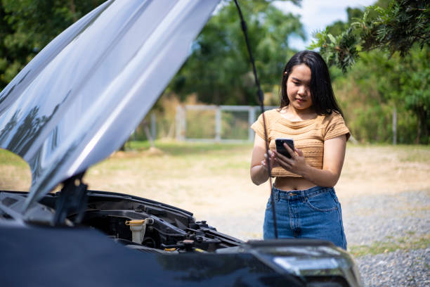 istock Young Asian woman using a mobile phone to call the mechanic while looking at broken down car on street. 1449339613