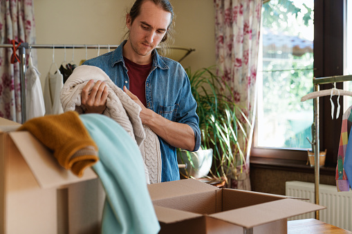 Man packing clothes into cardboard boxes to send it to client