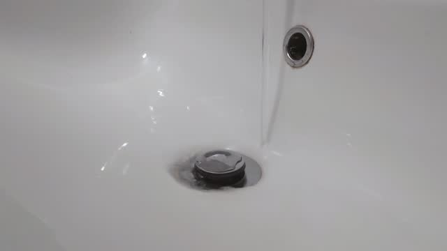 Water flows from the tap. Water saving. Washbasin drain drain. The water is flushed down the drain in the bathroom