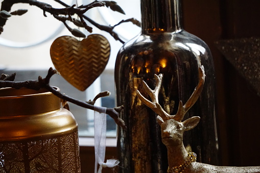 German traditional window sill decorations. A golden deer, a heart, a Christmas ball and a pine cone. A beautiful idea for home decor in a single golden color for Christmas and New Year and other winter holidays.