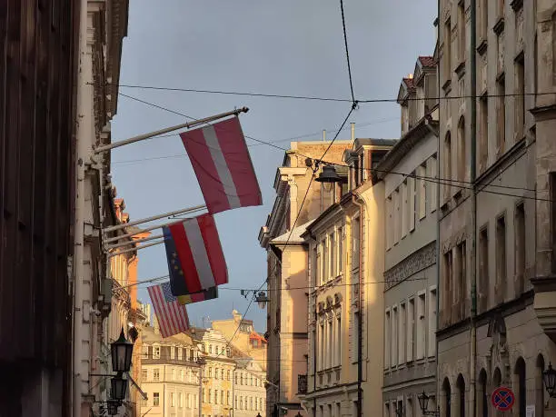 Photo of European architecture of Old town of Riga Latvia. Buildings in sunlight. Flags of Latvia, Austria, Germany, USA and EU on wall.
