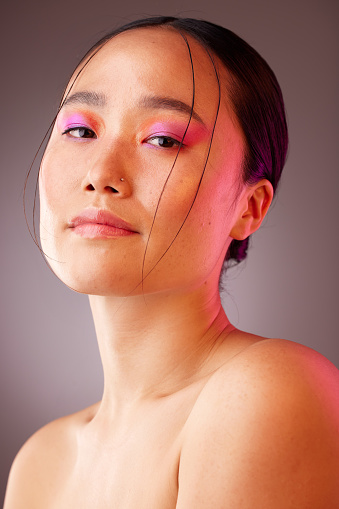 Woman with makeup, pink eyes shadow and luxury cosmetics product for beauty, skincare and creative facial design. Aesthetic, glamour and face of Asian girl with neon lights, glowing skin or self care