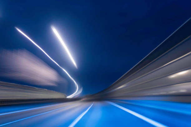 Car driving through an illuminated tunnel. Blurry long exposure of traffic. Inside point of view, no people.