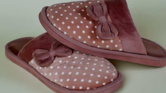 Women's house slippers with a beautiful pink pattern with white polka dots and a bow. Pair of female slippers for house. Modern indoor shoes for walking around the house, soft, warm and comfortable
