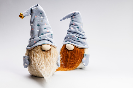 Two cute gnome in a cap on a light background. Handmade soft toy. Home decor. Copy space