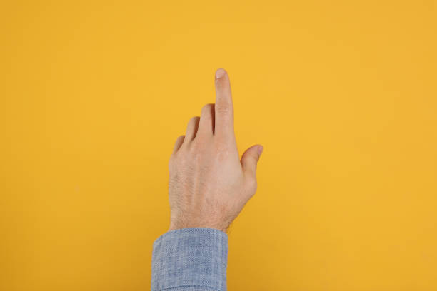 istock Man pointing at something against yellow background, closeup on hand 1449346856