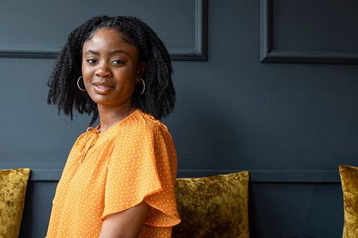 A young woman sitting in a modern restaurant in Amble, North East England. She is looking over her shoulder to the side, at the camera and smiling.