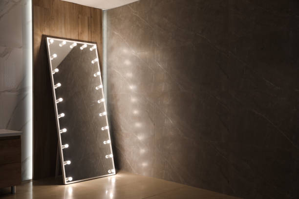 istock Modern mirror with light bulbs near wooden wall in room. Space for text 1449350330