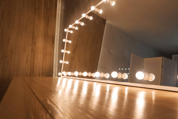 istock Modern mirror with light bulbs on wooden table in room, closeup 1449350527