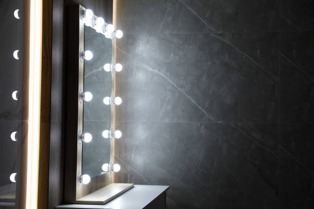 istock Modern mirror with light bulbs on grey chest of drawers in room. Space for text 1449350528
