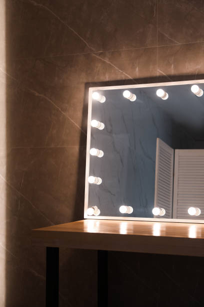 istock Modern mirror with light bulbs on wooden table in room 1449350764