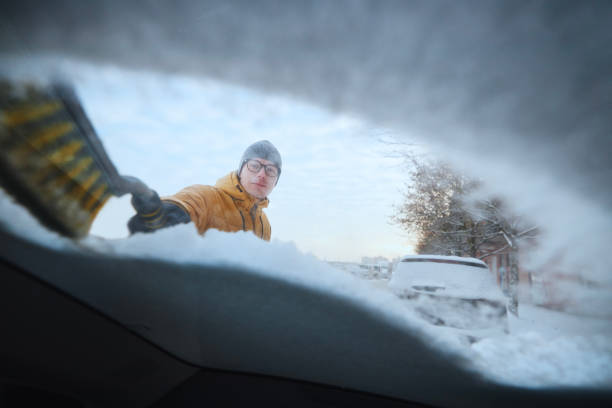 мужчина расчищает снег с лобового стекла своего автомобиля - window frozen car cold стоковые фото и изображения