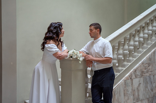 Lush, charming bride on the stairs. Stylish girl in wedding dress with bridal bouquet