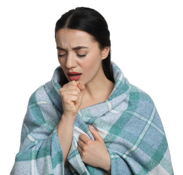 istock Young woman wrapped in blanket coughing on white background. Cold symptoms 1449354486