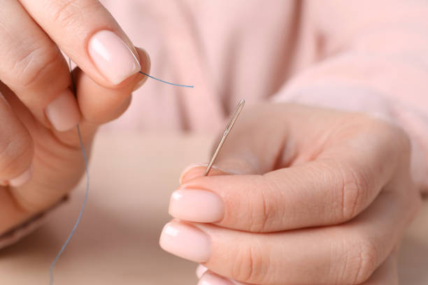 istock Woman threading sewing needle at table, closeup 1449355959