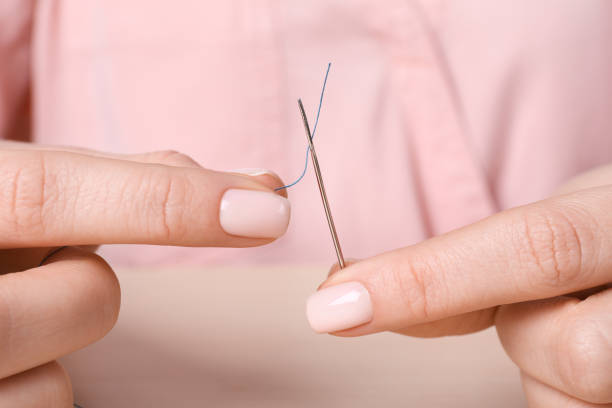 istock Woman threading sewing needle at table, closeup 1449355988