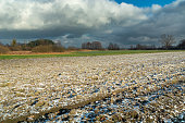 Small snow on a plowed field and cloudy sky
