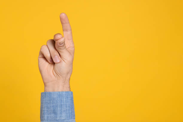 istock Man snapping fingers on yellow background, closeup of hand. Space for text 1449357456