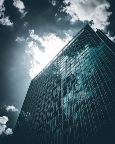 istock Modern office building from glass reflecting clouds during a sunny day, low angle 1449360266