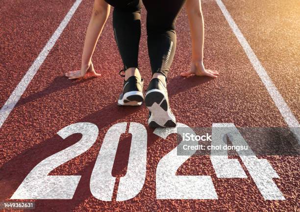 Rear View Of A Woman Preparing To Start On An Athletics Track Engraved With The Year 2024 Stock Photo - Download Image Now