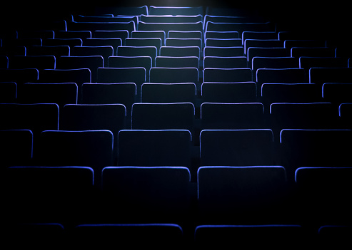 Empty movie theatre with blue light of the projector on the seats