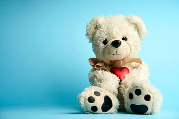 istock Teddy bear holding heart on blue background with copy space 1449367806