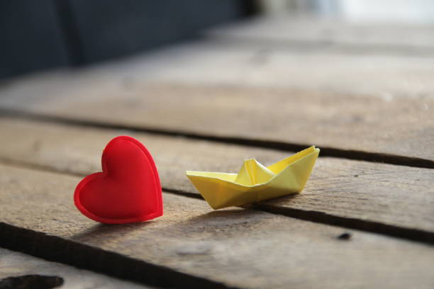 Red heart on a wooden background and paper boat. Place for text. Valentine. stock photo