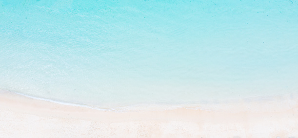 Coastline aerial photograph of aquamarine ocean and man walking along white sandbar beach in Australia