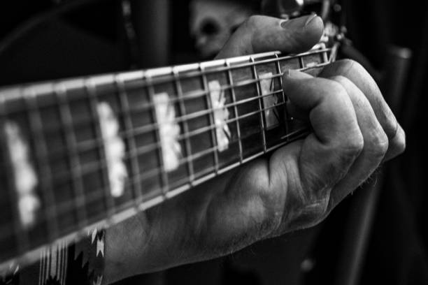 istock Grayscale closeup of a hand playing guitar. Guitar strings. 1449370974