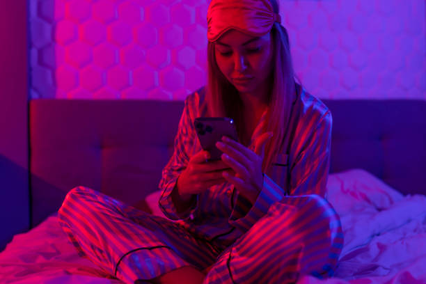 istock Using mobile phone in glowing neon light. Creative bright color ultraviolet red and blue. Woman's hands typing a message on a mobile phone 1449371127