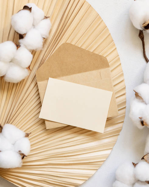 istock Blank card and envelope on dried palm leaf with cotton flowers top view, wedding mockup 1449373711