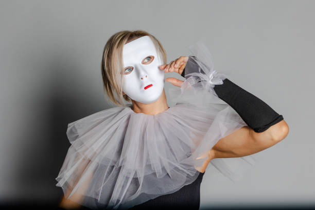 frau in weißer theatermaske und harlekinkragen auf grauem hintergrund. kostüme, maskerade kleidung - harlequin mask black sadness stock-fotos und bilder