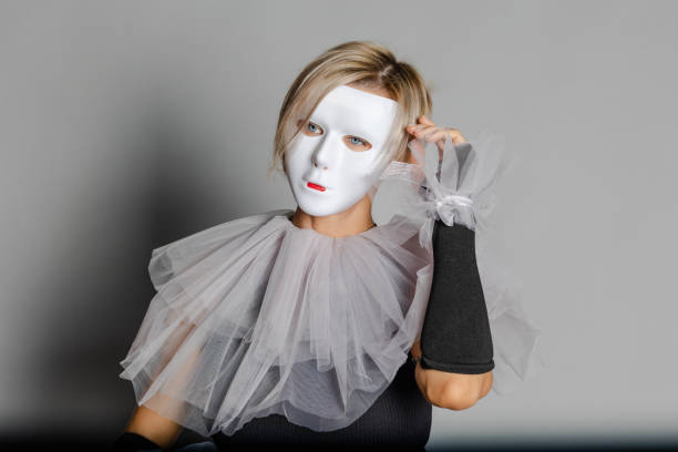 женщина в белой театральной маске и воротнике арлекина на сером фоне. нарядное платье, маскарадная одежда - harlequin mask black sadness стоковые фото и изображения
