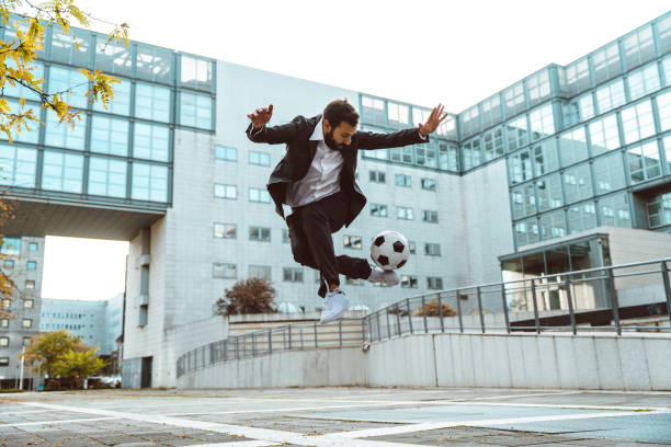 hombre de negocios jugando con una pelota de fútbol y haciendo trucos de estilo libre - suit soccer men sport fotografías e imágenes de stock