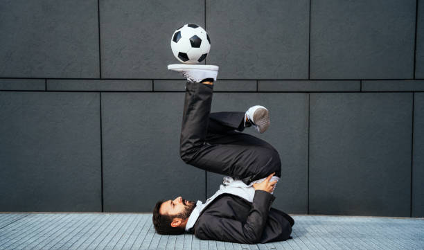 Image of a businessman and soccer freestyle player making tricks with the ball on the street. Concept about sport and business people